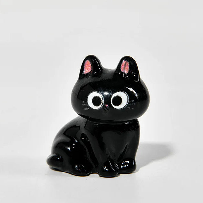 Black cat figurine with large eyes on a white background